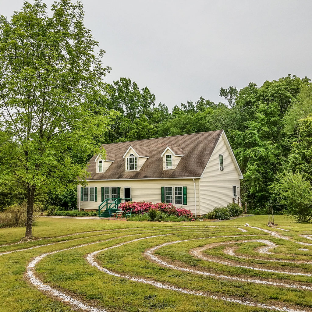 A house with a spiral labyrinth in the yard.