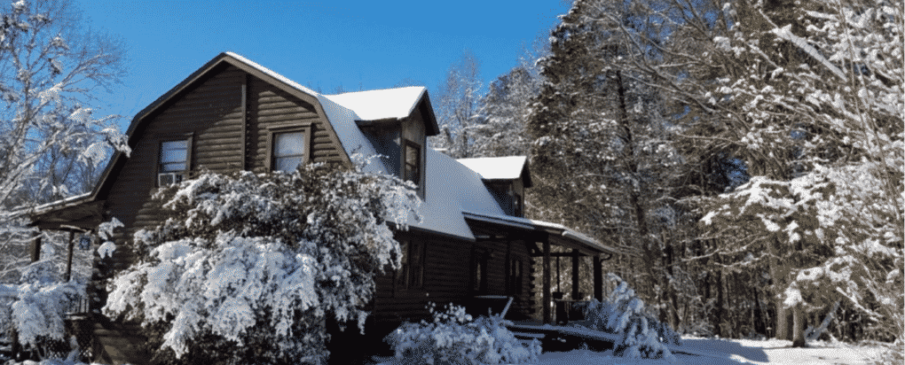 A house with snow on the roof and trees in the background.