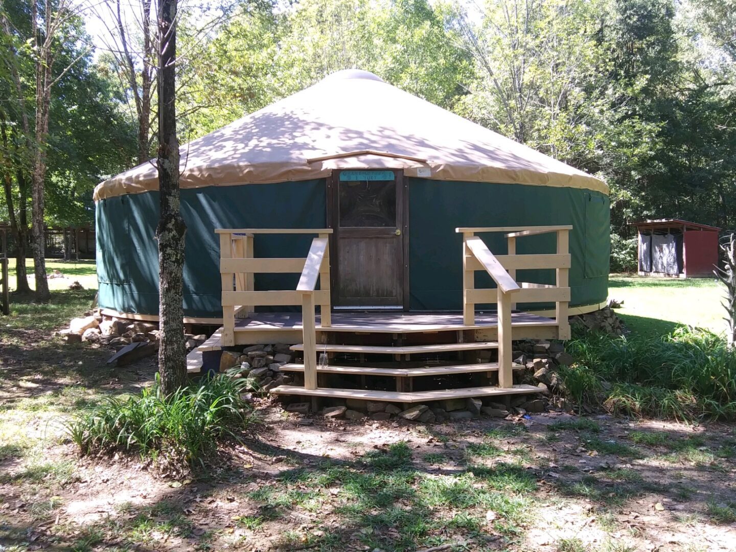 A green and brown yurt with steps leading to it.