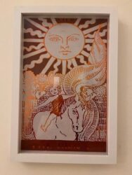 A framed picture of a sun and horse, reminiscent of scenes found near lodges in North Carolina.