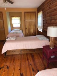 A bedroom with two beds and wooden floors.
