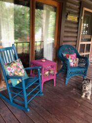 A dog sitting on the porch of a cabin.