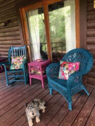 A cat laying on the porch of a log cabin.